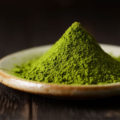 Matcha powder shaped into a green mound in a shallow bowl – moody lighting, detailed close-up