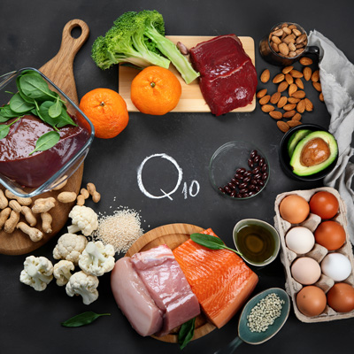 Various foods like fish, eggs, meat, vegetables and nuts arranged around “Q10” text – even lighting, informative overview 