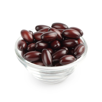 Dark red capsules in small glass bowl against light background – even lighting, clean product shot