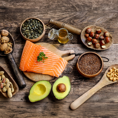 Salmon, avocado, nuts and seeds arranged on wooden table – natural light, diverse and balanced food composition