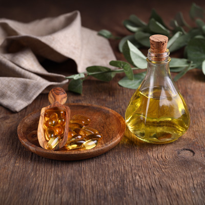 Ölflasche und Kapseln in Schale auf Holztisch – warmes Licht, minimalistische und natürliche Darstellung 