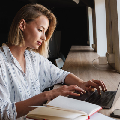 Gedankenklarheit trifft Pflanzenkraft Junge Frau arbeitet fokussiert am Laptop mit Notizbuch – Symbol für Konzentration, mentale Leistung und Produktivität