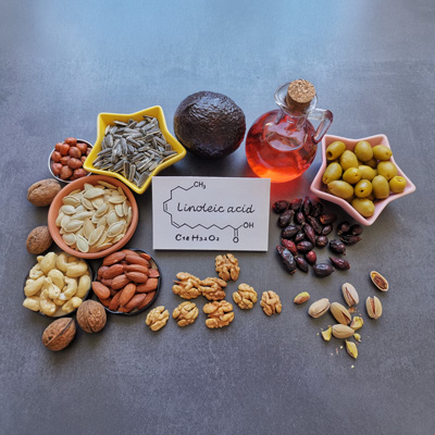 Various nuts, seeds and oils arranged around linoleic acid formula – even lighting, informative food overview