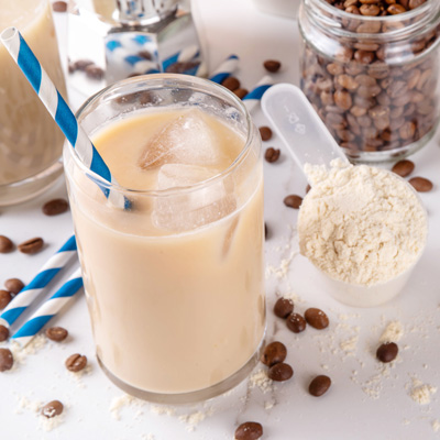 Creamy iced coffee with caffeine powder, coffee beans and scoop – bright studio light