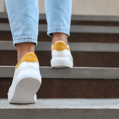 Person in Jeans und weißen Sneakern steigt eine Treppe hinauf – Bewegung im Alltag