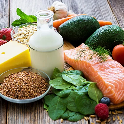 Lachs, Avocados, Spinat, Beeren und weitere Lebensmittel für eine entzündungsbewusste Ernährung auf Holztisch