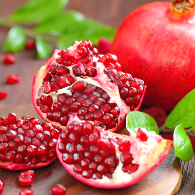 Cut pomegranate with shiny seeds on wooden surface – natural light, fresh and vibrant color tones