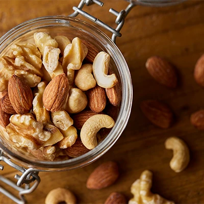 Jar filled with almonds, walnuts, cashews and hazelnuts on a wooden table – warm, natural atmosphere
