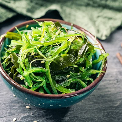Green seaweed salad with sesame seeds in a ceramic bowl – fresh close-up in natural light