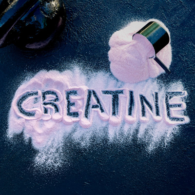 Wort „Creatine“ in hellem Pulver neben Messbecher – kreative Darstellung auf dunklem Grund