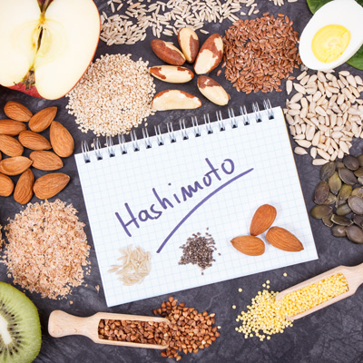 Notizzettel mit „Hashimoto“ zwischen Nüssen, Samen und Lebensmitteln – natürliche Bildwirkung