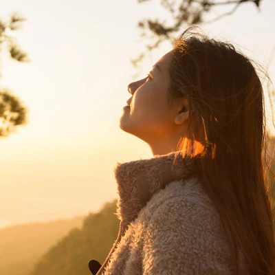Frau hält ihr Gesicht ins warme Sonnenlicht – natürliche Aufnahme zum Thema Vitamin D und Sonne