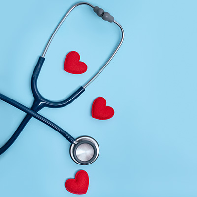 Stethoscope with red hearts on light blue background – symbol of the cardiovascular system