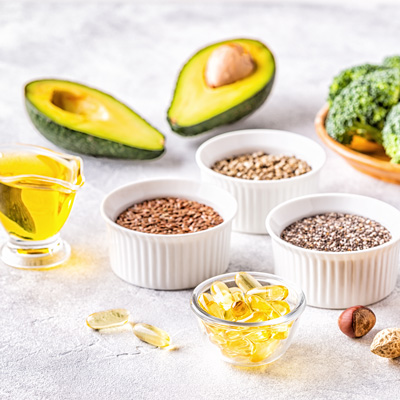 Avocado, seeds, oil and capsules on light surface – soft light, natural and clean food arrangement