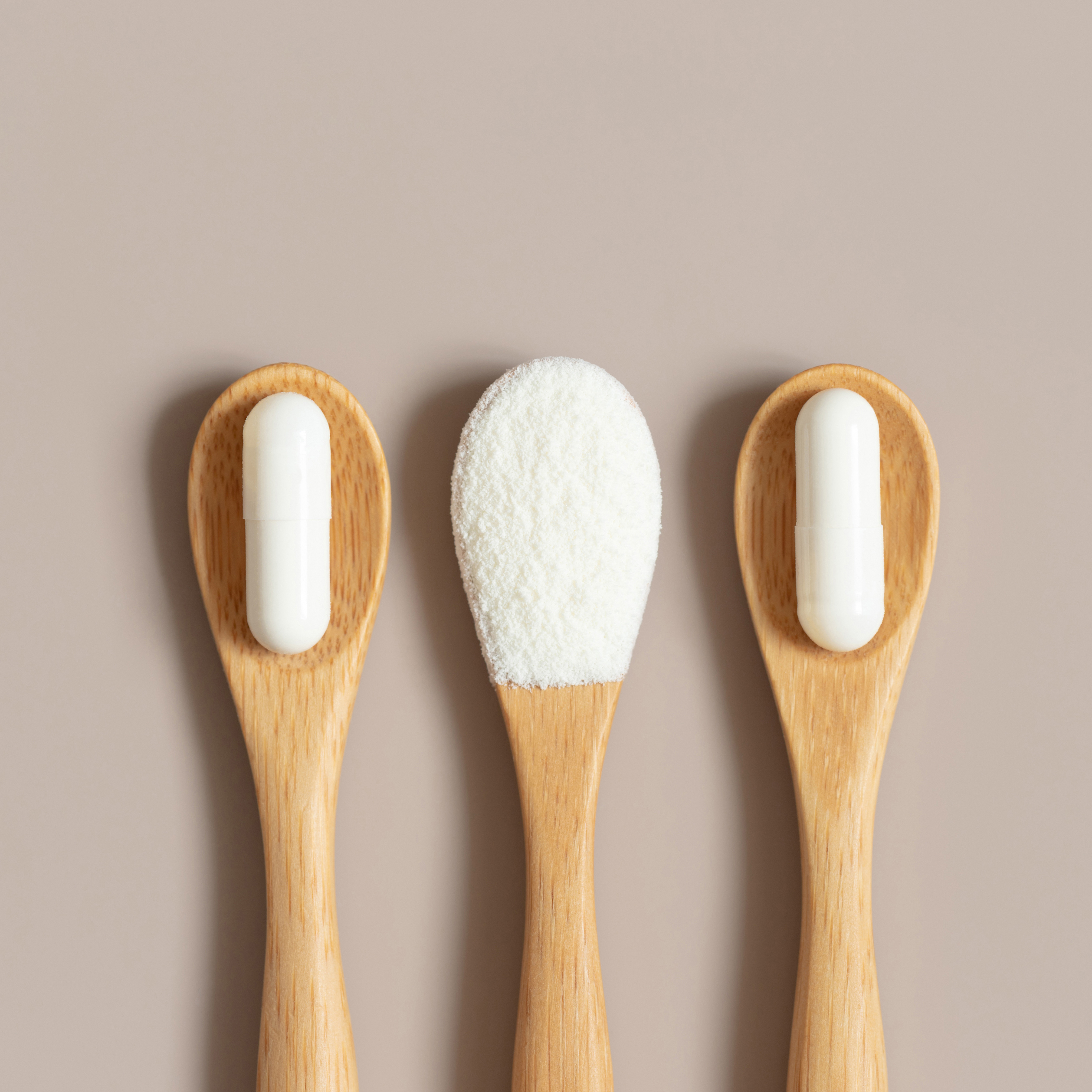 Glutathion-Pulver und weiße Kapseln auf Holzlöffeln – natürliche Produktaufnahme
