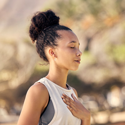 Frau mit geschlossenen Augen atmet ruhig im Freien – warmes Sonnenlicht, entspannte und ausgeglichene Stimmung 