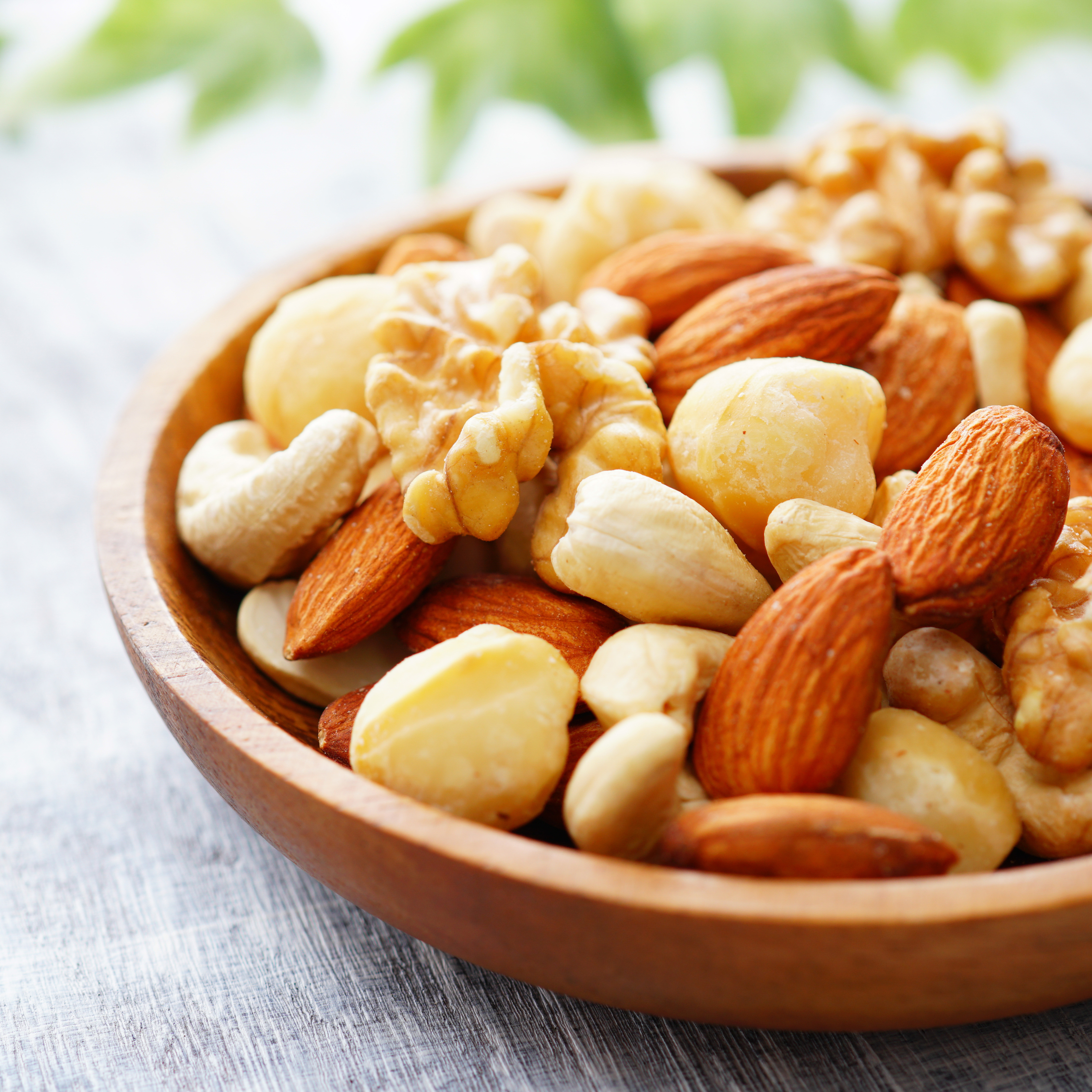 Gemischte Nüsse mit Mandeln, Walnüssen, Cashews und Macadamianüssen in einer Holzschale