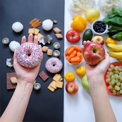 Hände halten Donut und Apfel vor ungesunden und gesunden Lebensmitteln – Vergleich der Ernährung