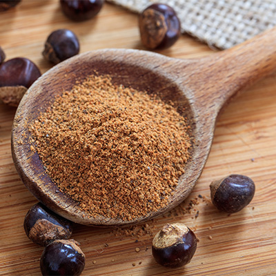 Guarana powder on wooden spoon with seeds – natural close-up on wooden surface